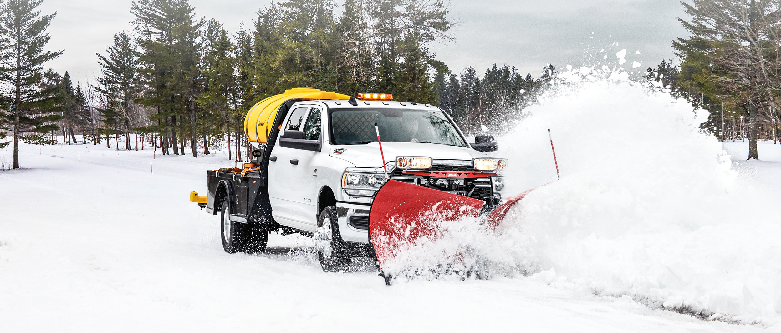 Front view of the 2020 Ram Chassis Cab in white plowing snow on a forest road