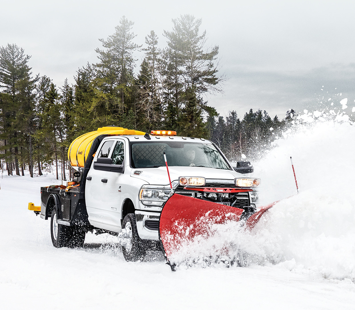 Front view of the 2020 Ram Chassis Cab in white plowing snow on a forest road