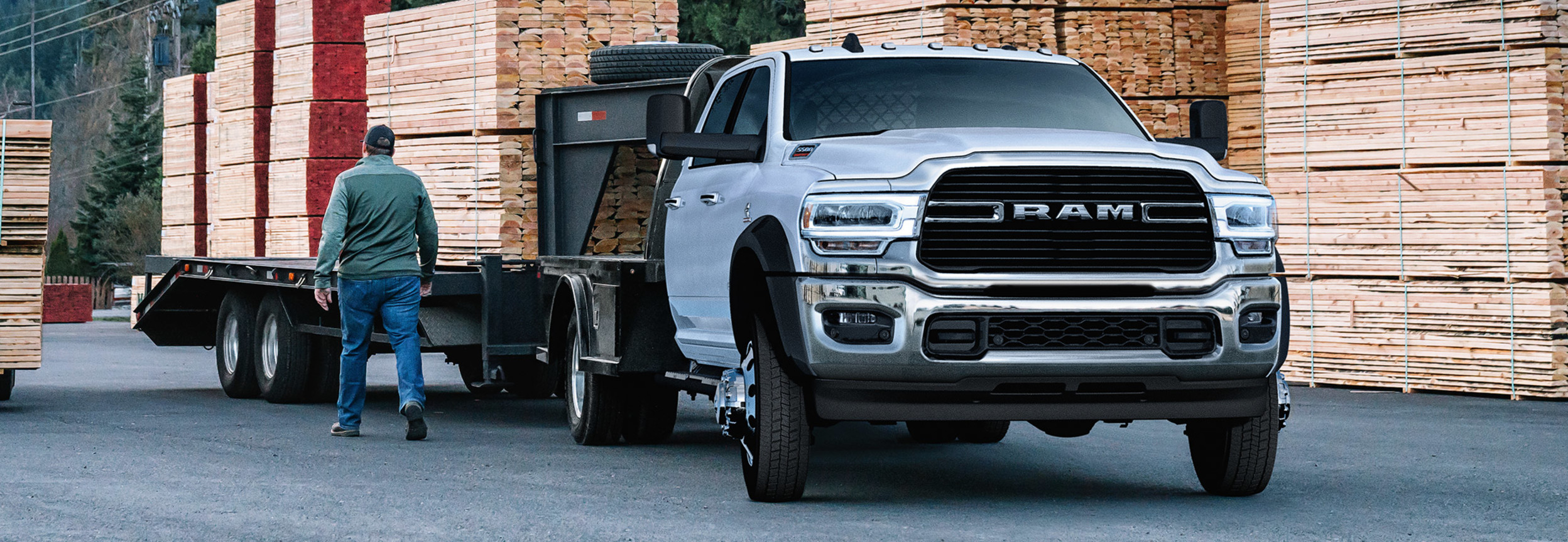 Front view of a silver RAM Chassis Cab being prepared to tow heavy wooden planks