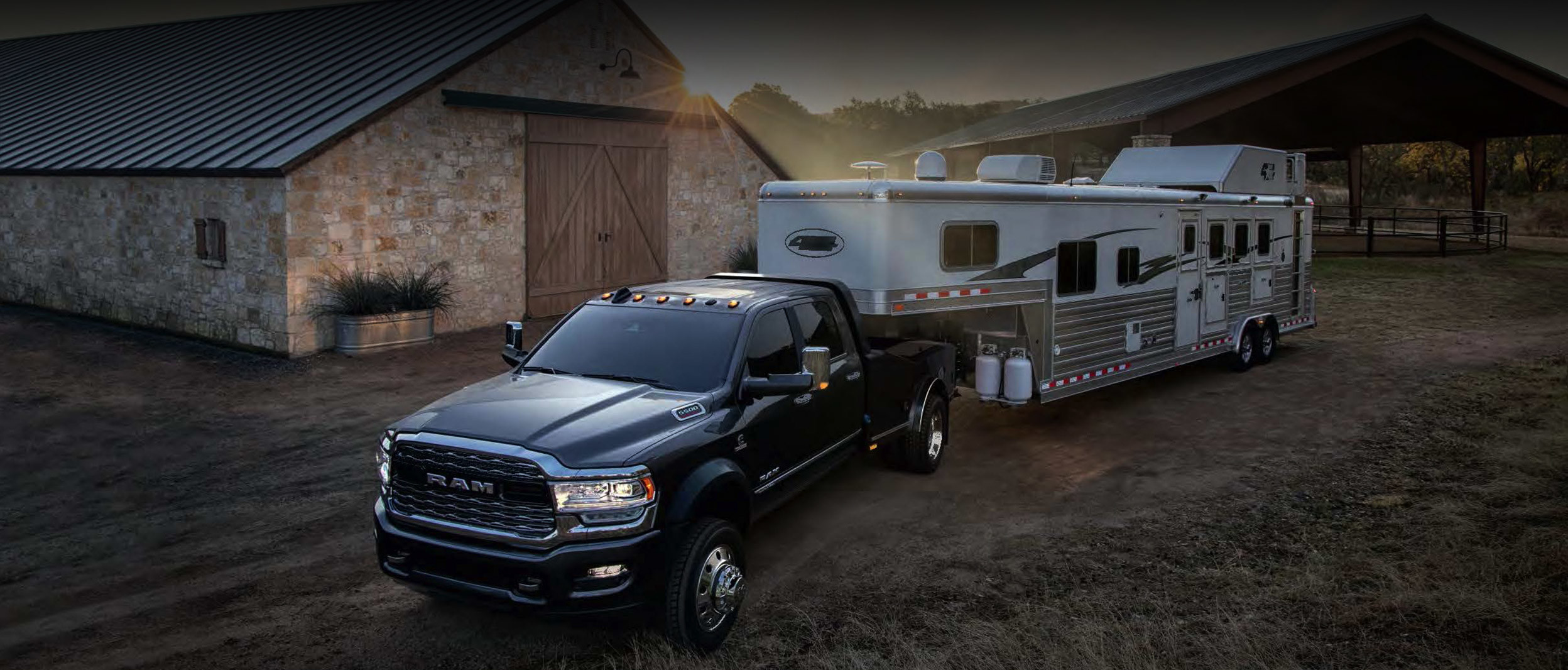 The black 2020 Ram Chassis Cab connected with camp trailer parked in front of barnyard