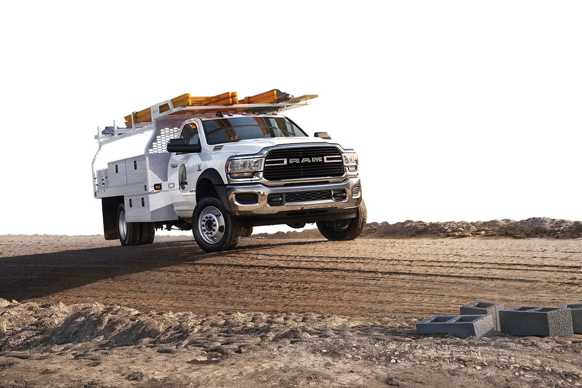 A front view of a Bright White 2021 Ram Chassis Cab equipped with a utility rack parked at a construction site.