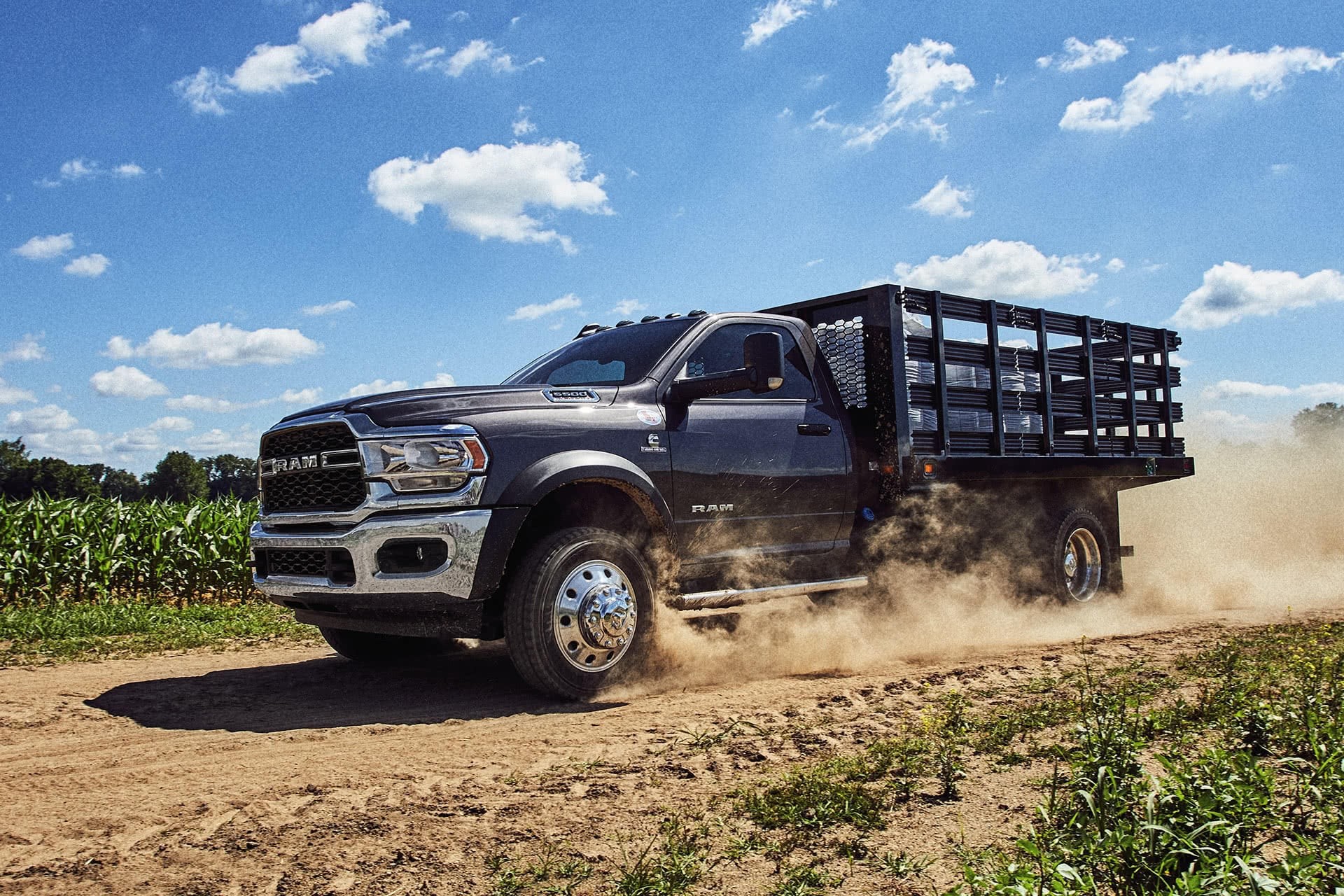 Châssis-cabine Ram 2021 couche nacrée bleu de Prusse roulant sur une route de terre dans un champ agricole.