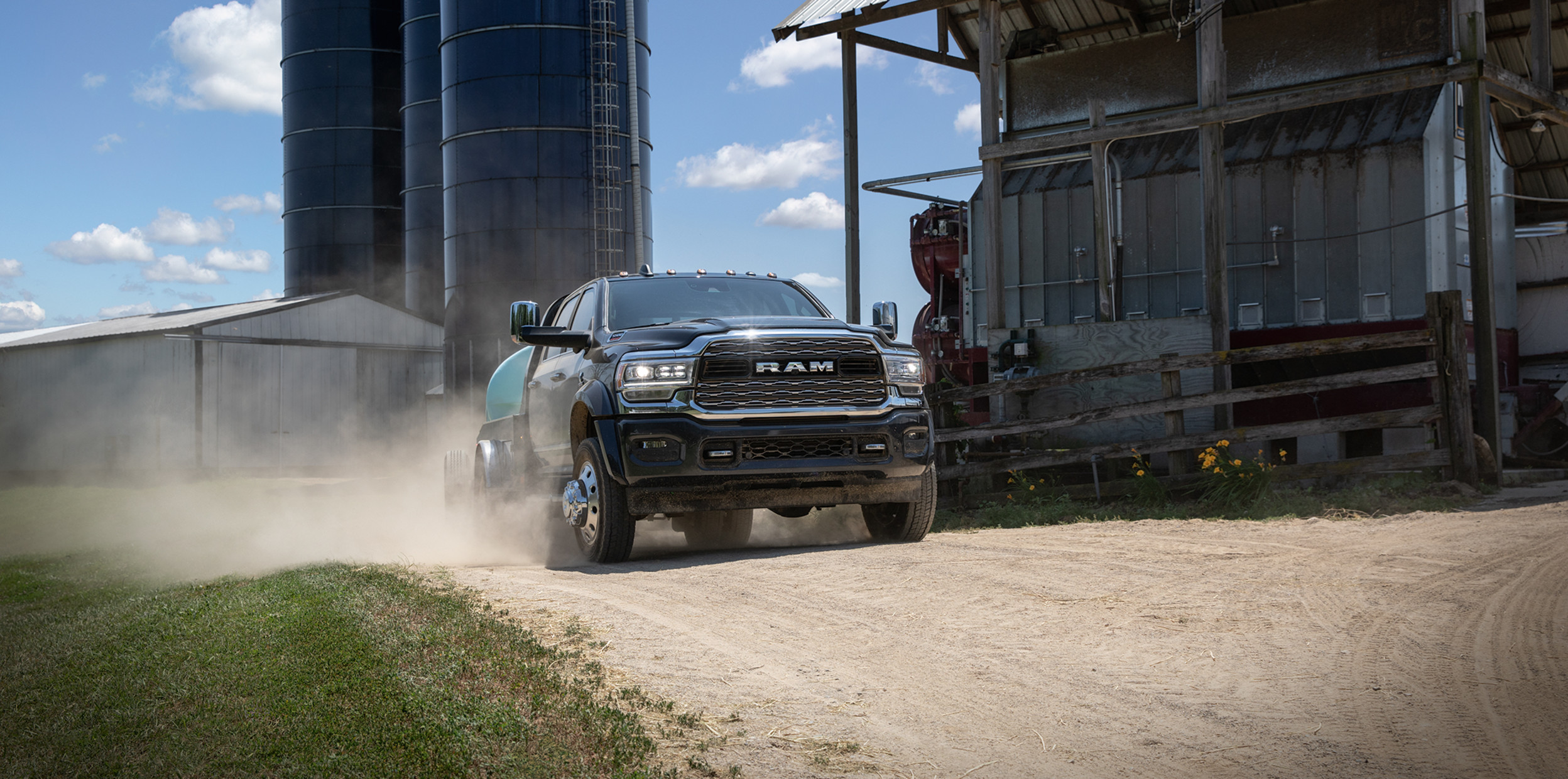 A black 2022 Ram Chassis Cab being driven on a dirt road through an industrial area.