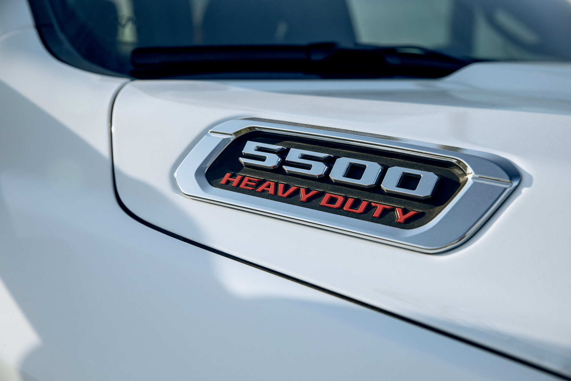 Un gros plan de l’emblème Ram 5500 Heavy Duty sur le capot d’un Ram châssis-cabine 2022 blanc éclatant.