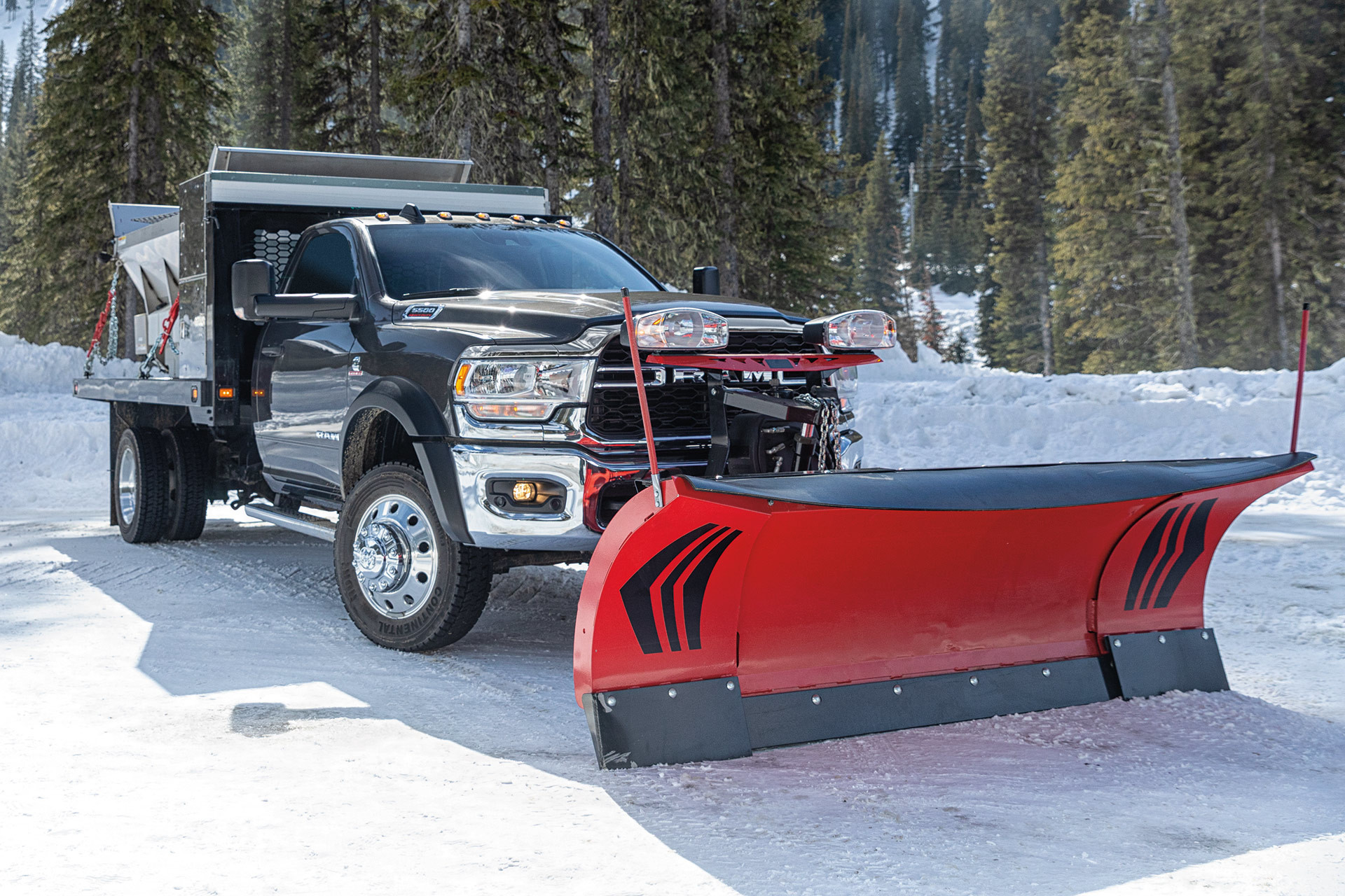 Châssis-cabine 5500 SLT 2022 de couleur cristal granite métallisé avec une benne soulevée et un chasse-neige, stationné dans une forêt enneigée par une journée ensoleillée, avec des arbres et des montagnes en arrière-plan.