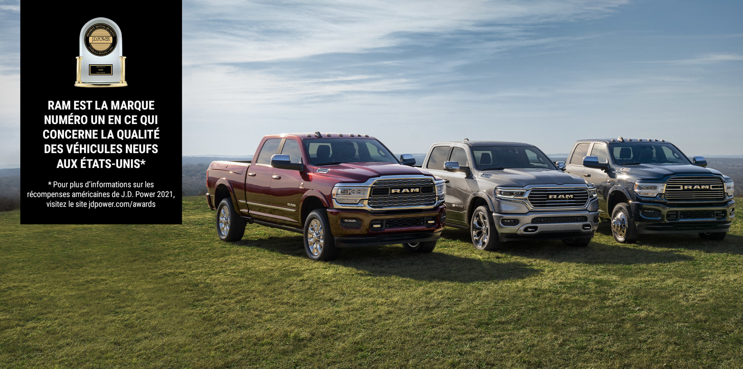 Un Ram 1500, 2500 et 3500 garés sur une plaine gazonnée avec une bannière du prix J.D. Power annonçant "Ram est la marque numéro un en ce qui concerne la qualité des véhicules neufs aux États-Unis."