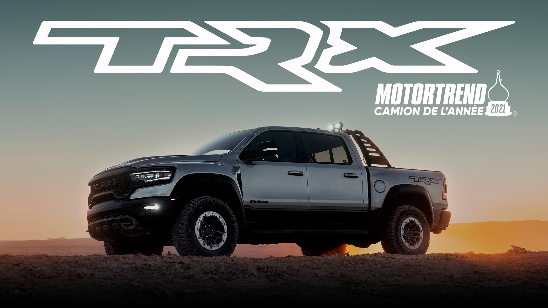 Vue latérale d’un Ram 1500 TRX argent sur une route poussiéreuse, le soleil se couchant en arrière.