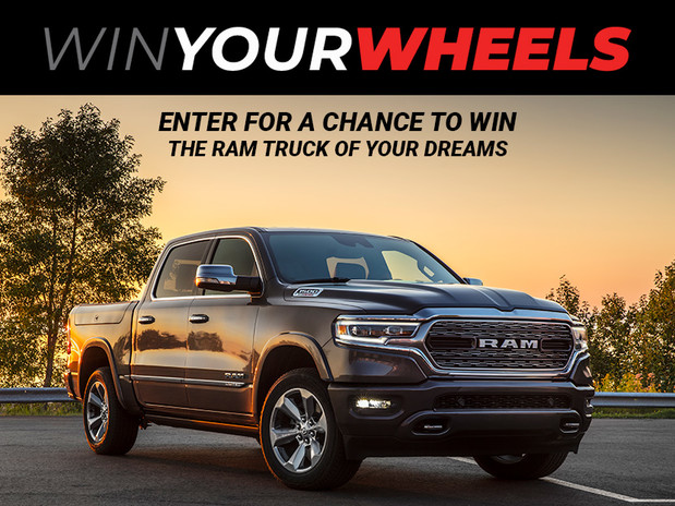 Front view of the 2020 Ram 1500 in black parked in front of the lake at sunset with the "Win Your Wheels" logo on top.