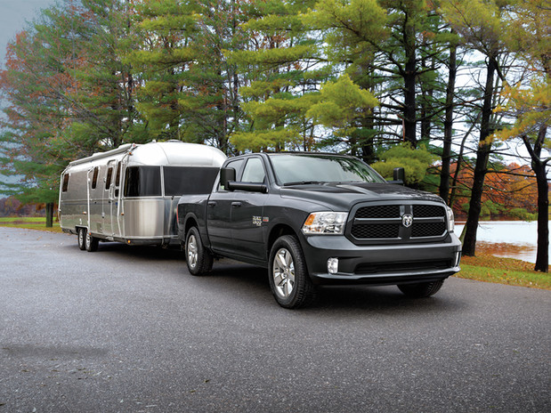 Ram 1500 Classic 2022 noir tirant une remorque sur une route pavée avec des arbres à l’arrière-plan.