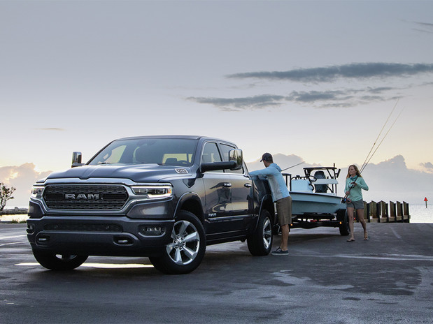 Vue d'un homme et d'une femme près d'un Ram 1500 2022 noir remorquant un bateau près d'un quai.
