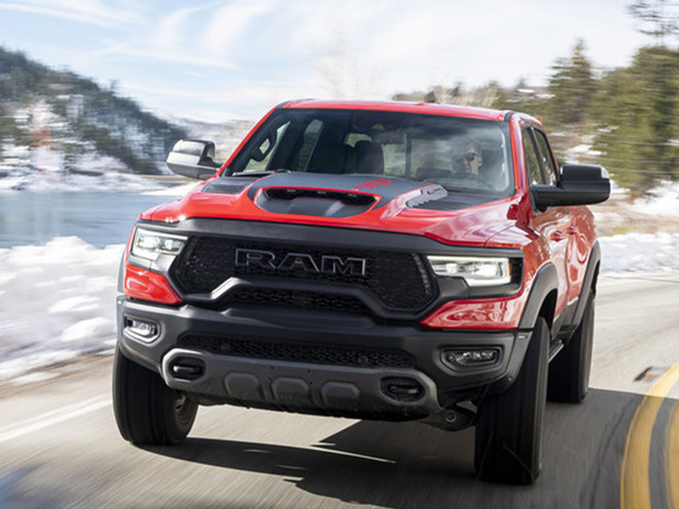 Vue de face d'un Ram 1500 2023 rouge roulant avec des montagnes, de la neige et des arbres en arrière-plan.