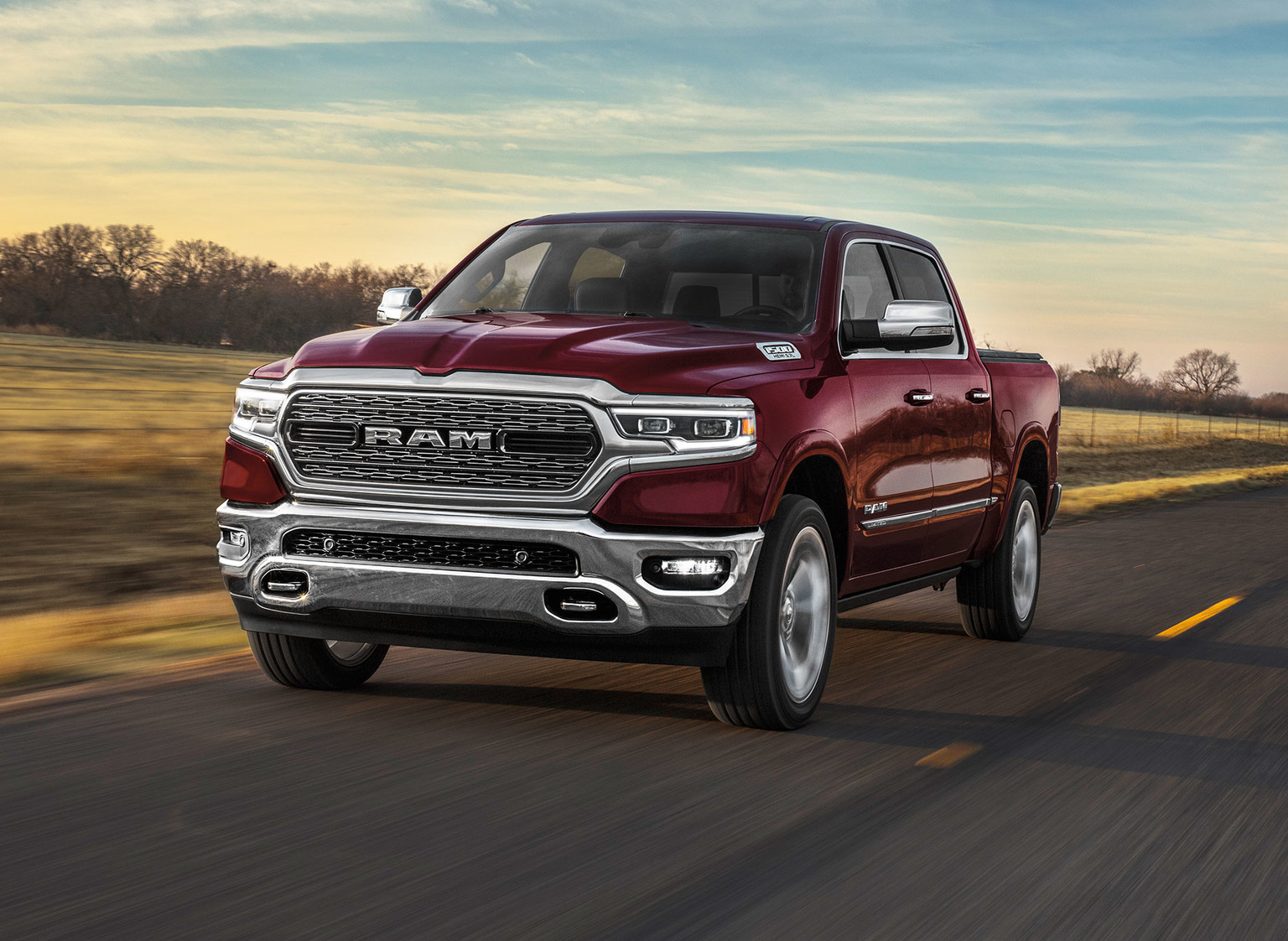 Front three quarter view of red pearl the All-New 2019 Ram 1500 driving on a road through plain