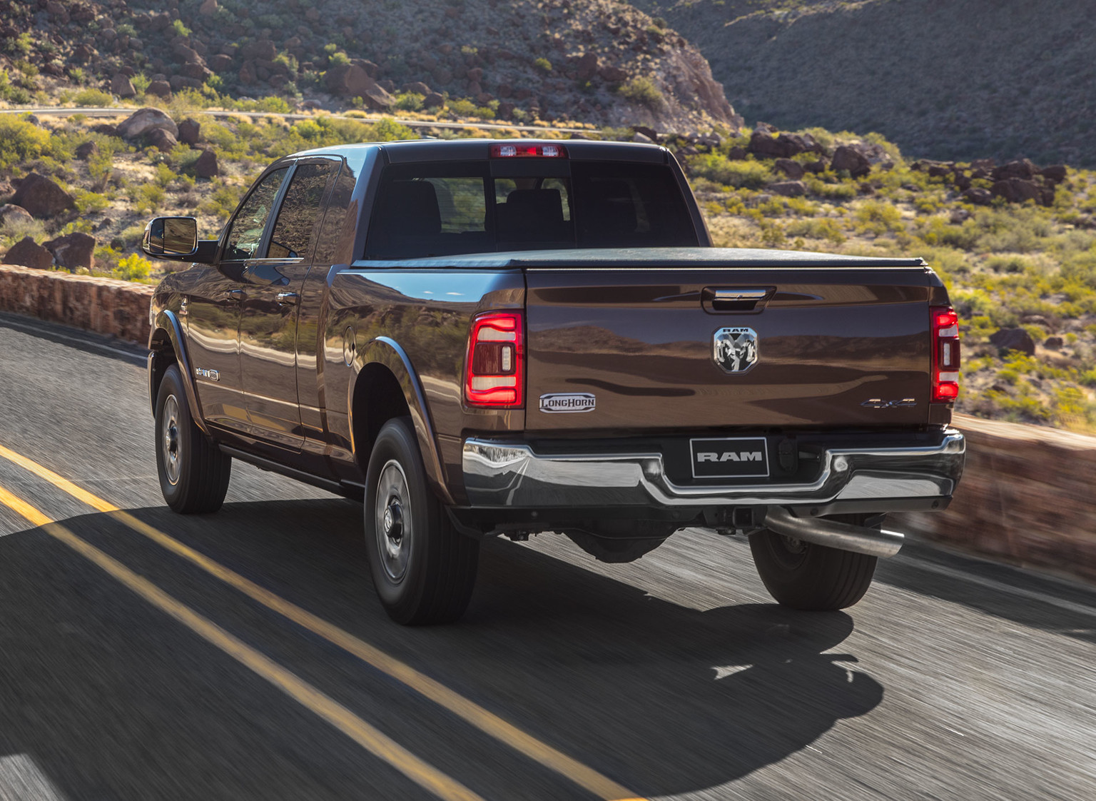 Rear quarter view of brown 2019 Ram HD pickup Truck driving on a road through the mountain