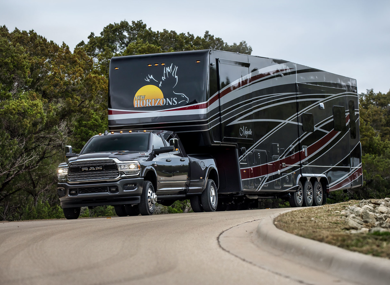 Black 2019 Ram HD pickup Truck Towing a black camping trailer driving through plain