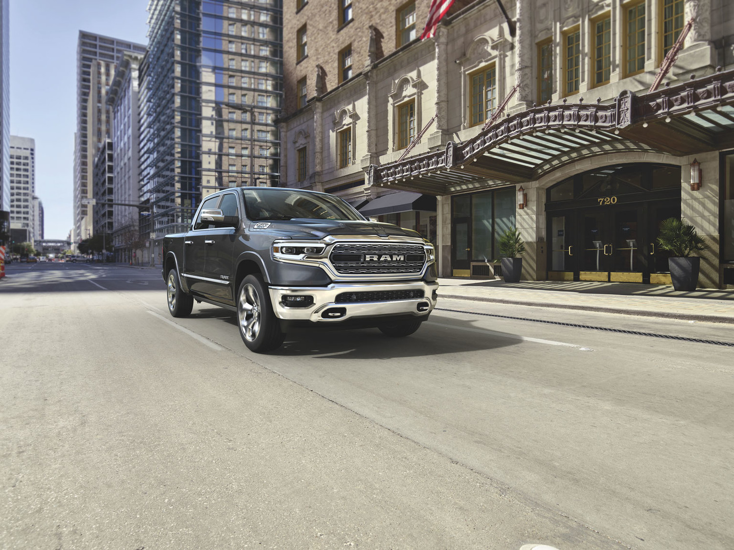 A grey Ram 1500, parked in front of a hotel building in the city.