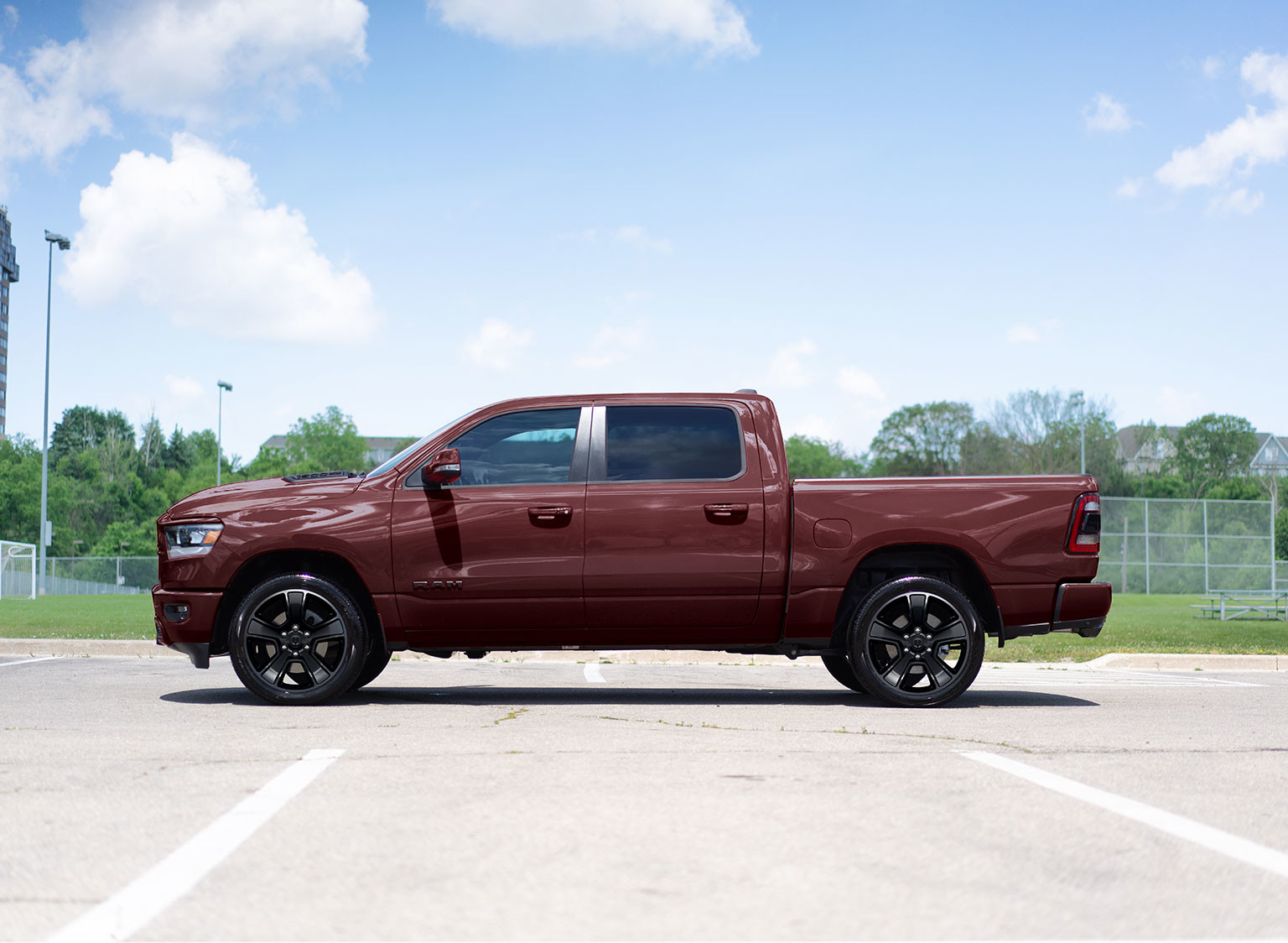 Une vue de côté d’un Ram 1500 Sport 2024, garé devant un champ.