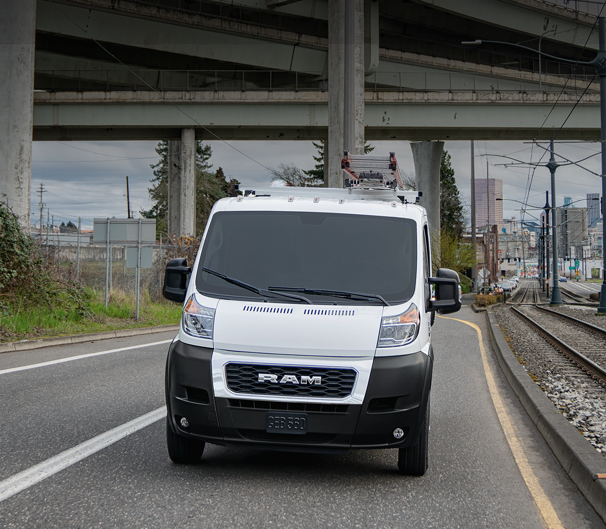 Vue de face du Ram ProMaster 2019, illustré en blanc, roulant sur une route à proximité des voies ferrées