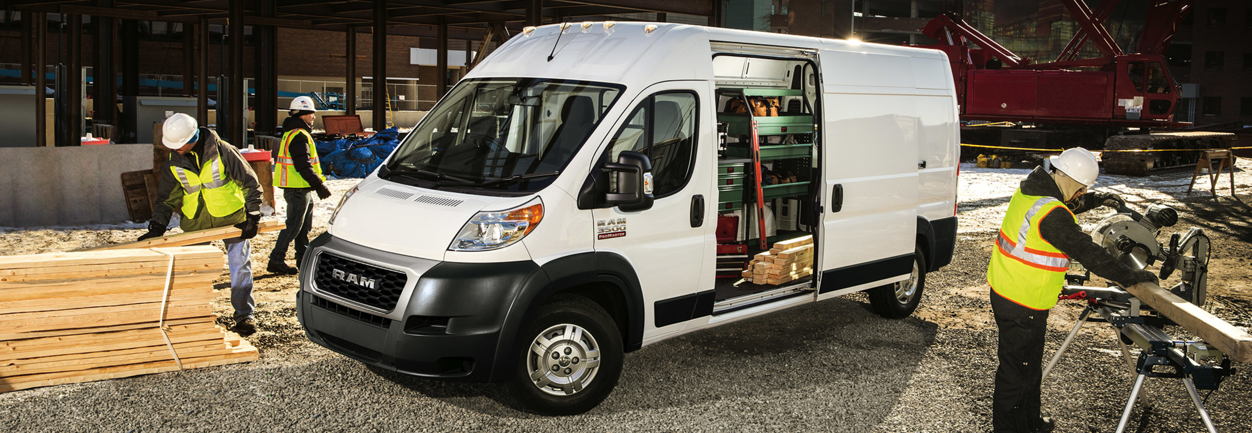 Side view of a white RAM ProMaster parked at a construction site with its side door open