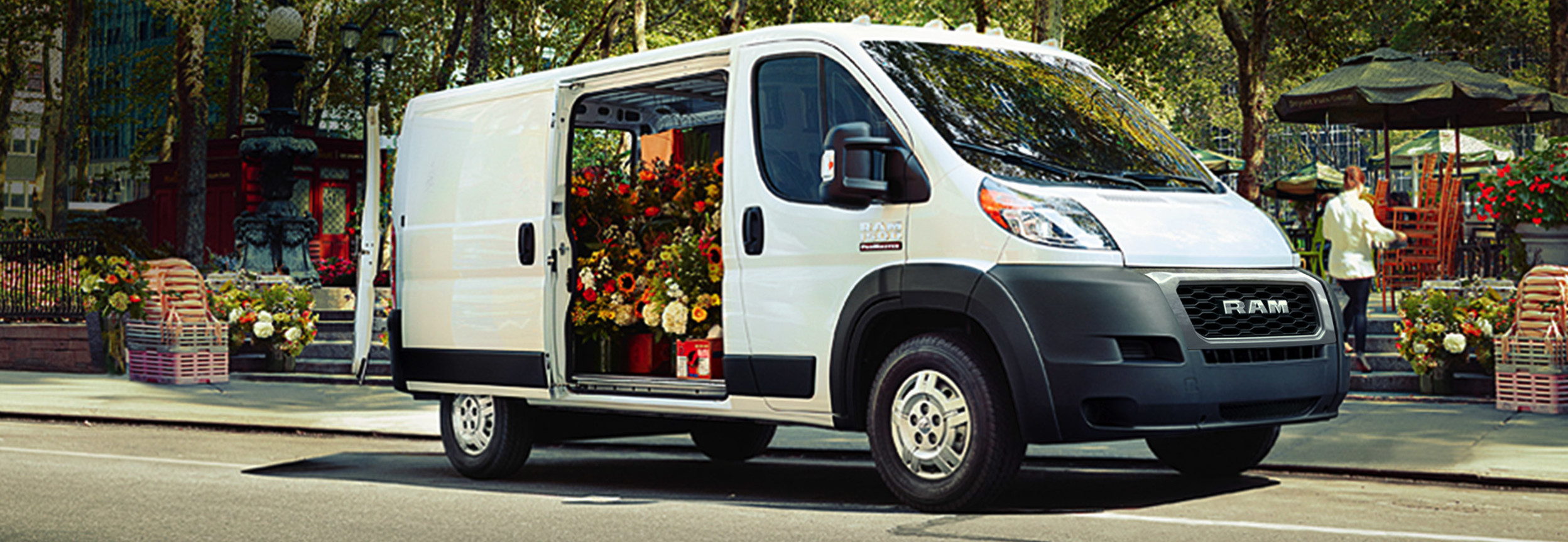 Side view of a parked white RAM ProMaster filled with flowers that has its side door open