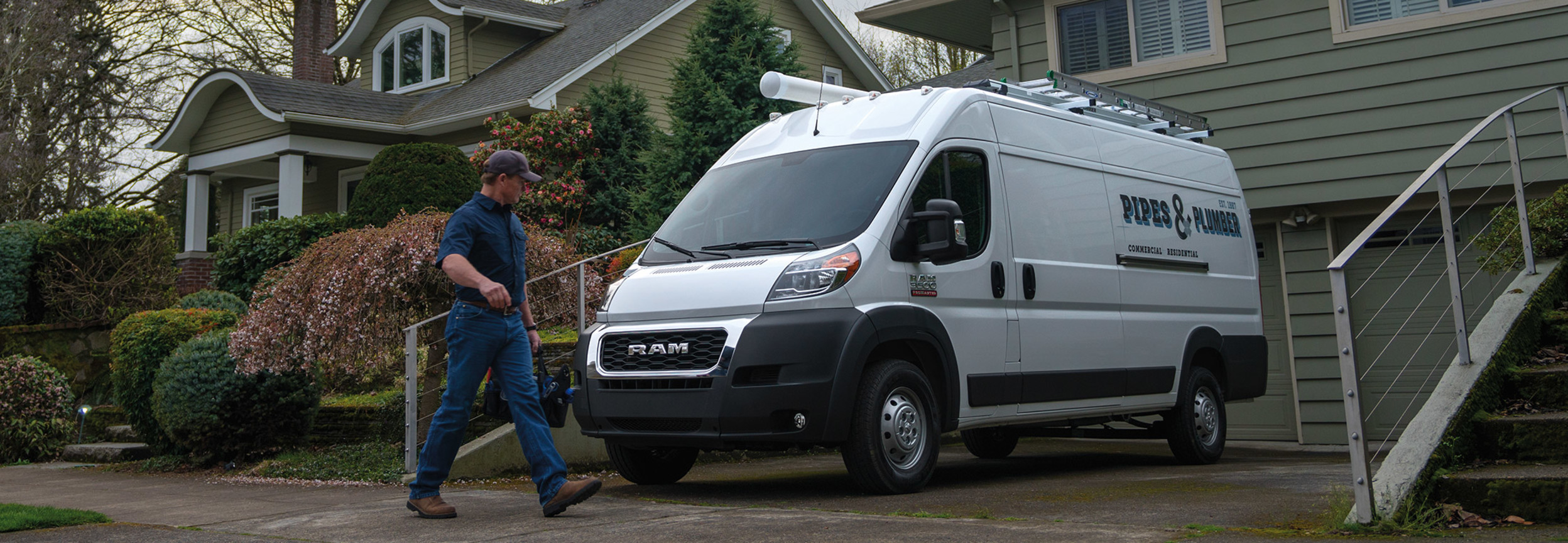 A white RAM ProMaster parked in the driveway of a suburban house