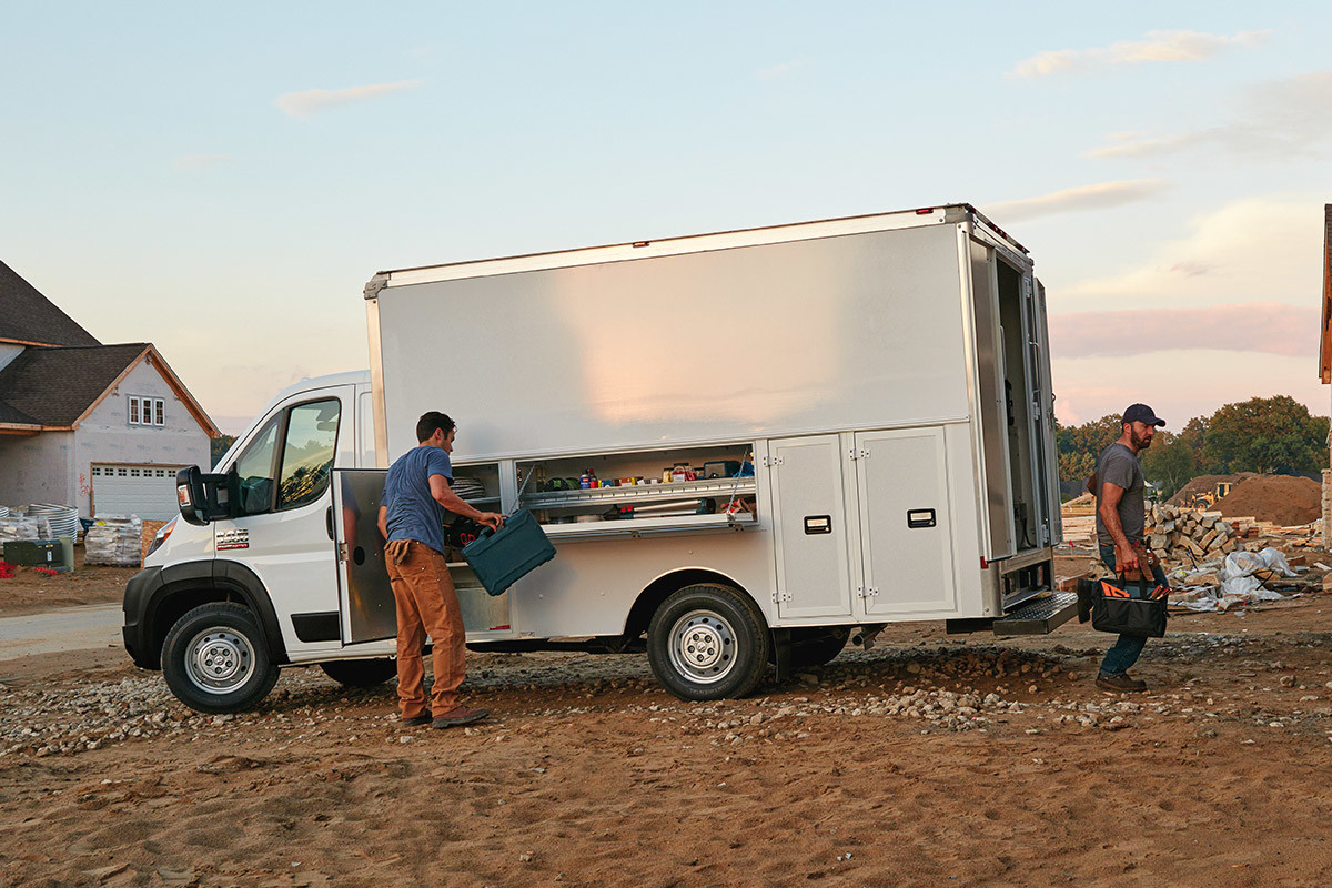 Le châssis-cabine Ram ProMaster 2020 blanc stationné à l’extérieur d’un chantier, pendant que deux hommes déchargent des marchandises