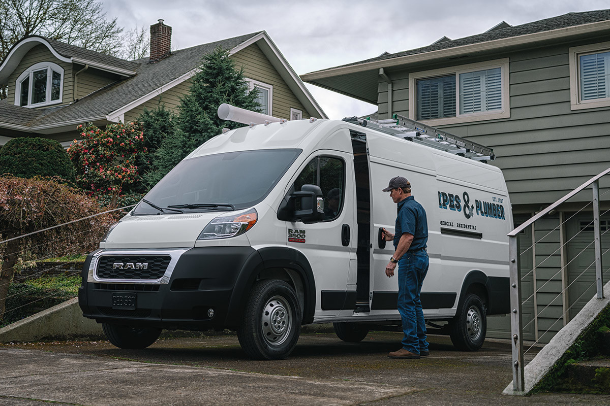 The white 2020 Ram ProMaster parked on a driveway while man is opening its side doors