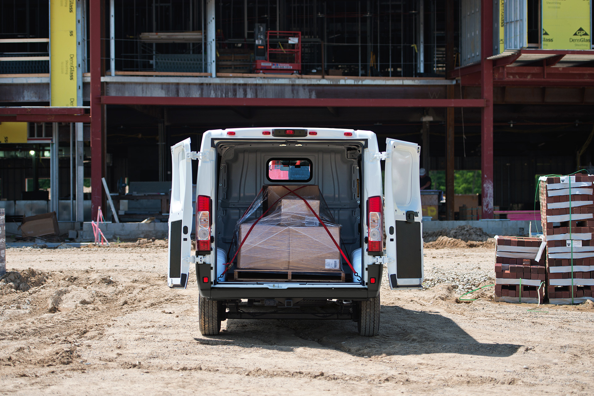 Le Ram ProMaster 2020 blanc stationné sur un chantier pendant que les marchandises sont chargées à l’arrière