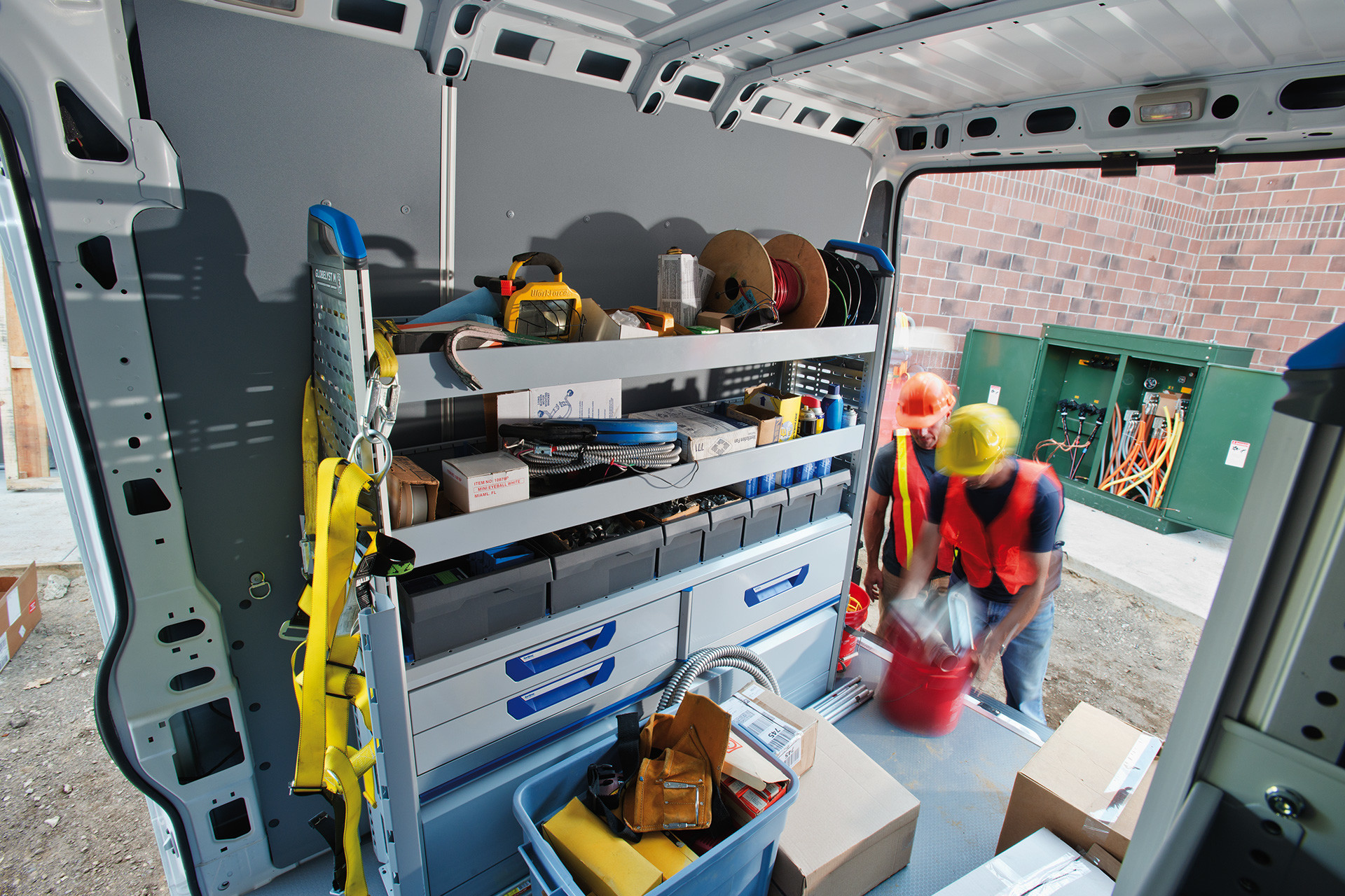 Espace utilitaire du Ram ProMaster 2020 avec des outils de construction sur les parois et deux hommes chargeant des marchandises