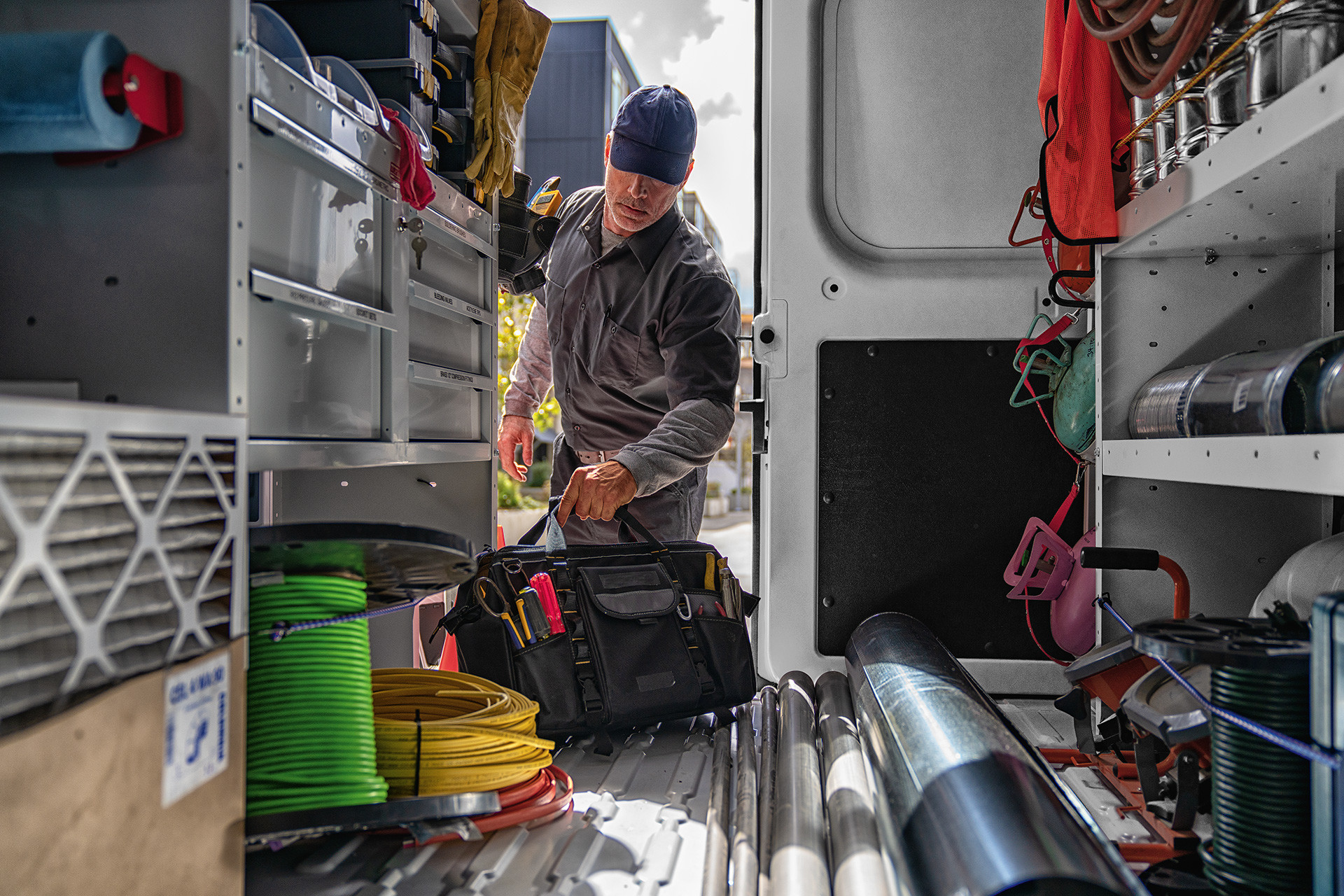 Un homme décharge un sac de l’espace utilitaire du Ram ProMaster 2020 rempli d’outils de construction