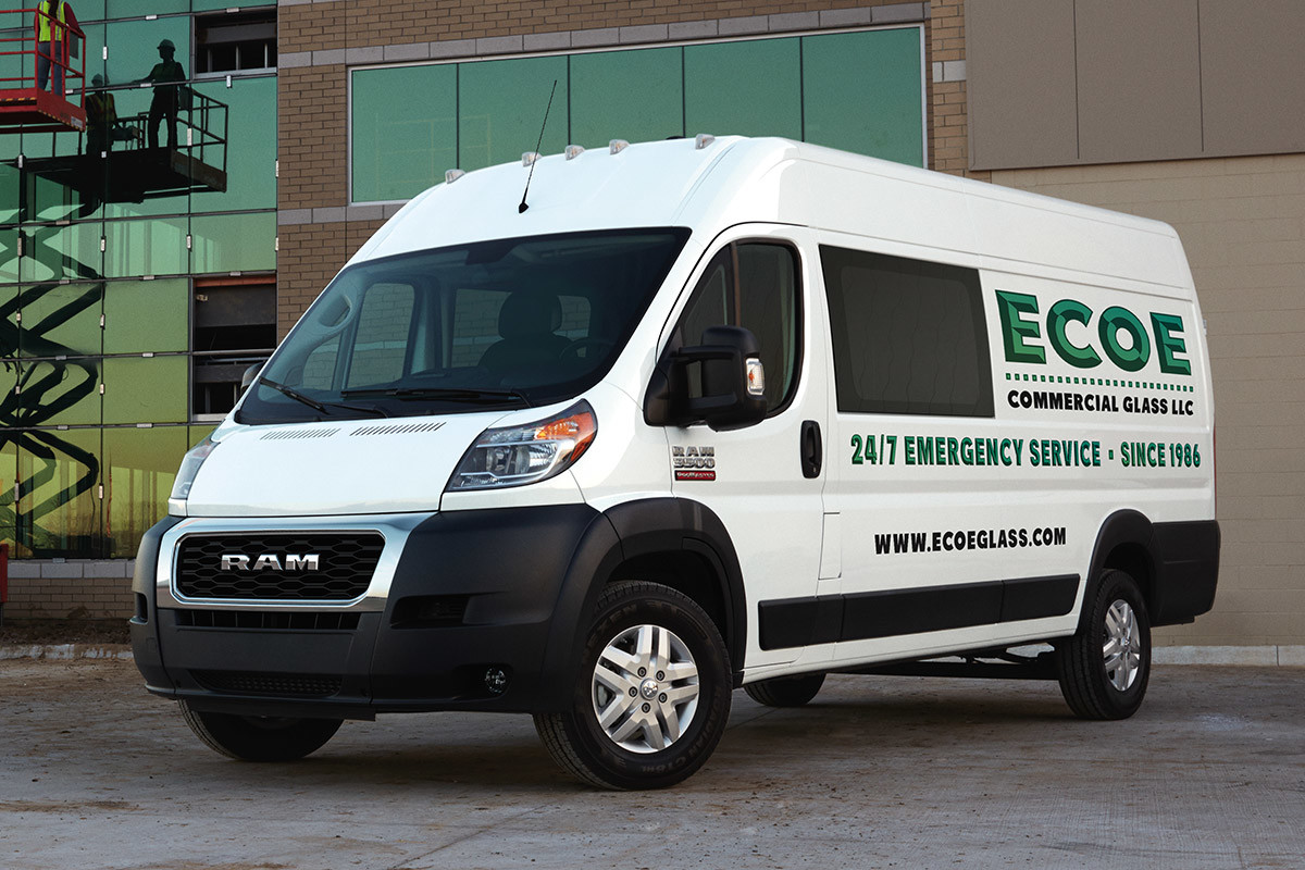 Ram ProMaster stationné devant un bâtiment avec trois ouvriers sur une table élévatrice en arrière-plan.
