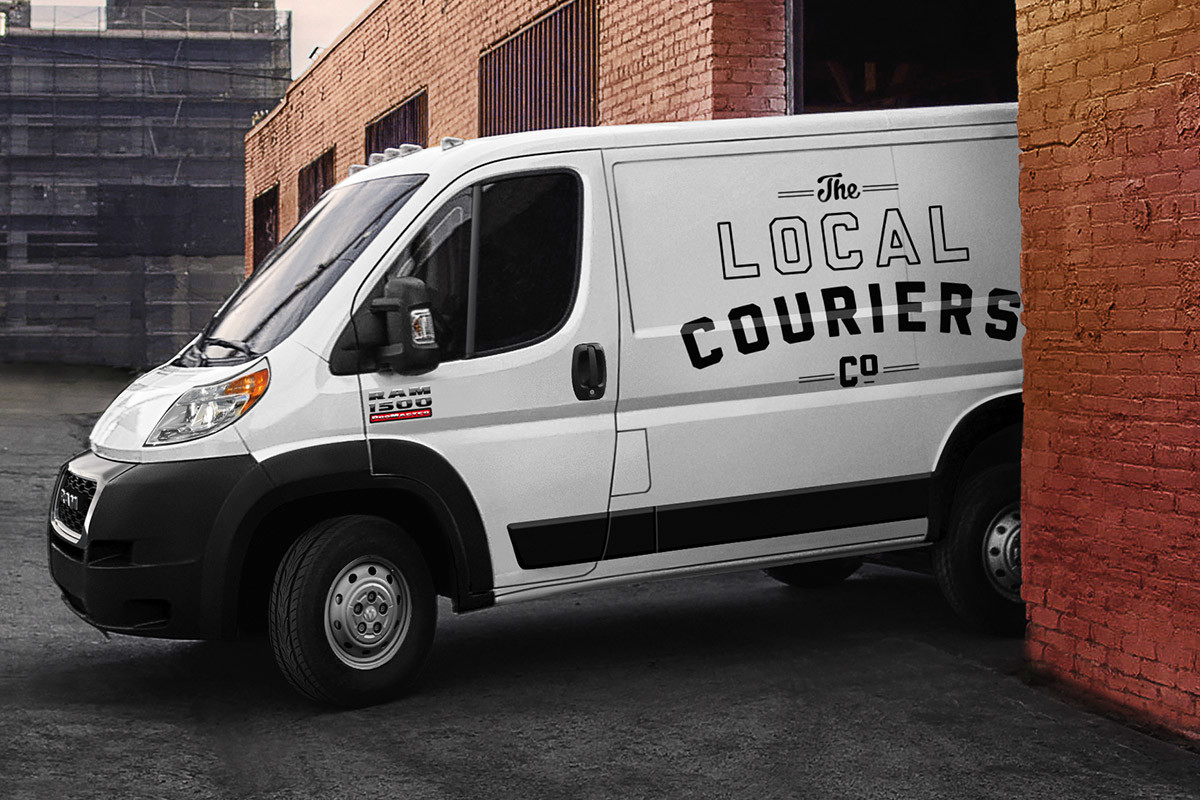 Ram ProMaster with ‘Local Couriers Co’ printed on the side exits the garage of an industrial building.