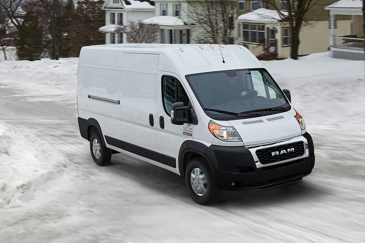 Ram ProMaster driving down a snowy residential road.