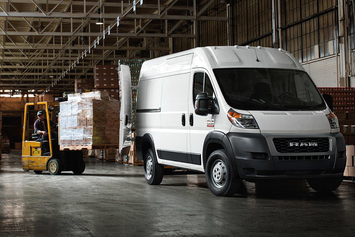 Ram ProMaster parked in a warehouse with the back doors open. A man uses a forklift to load boxes into the vehicle.