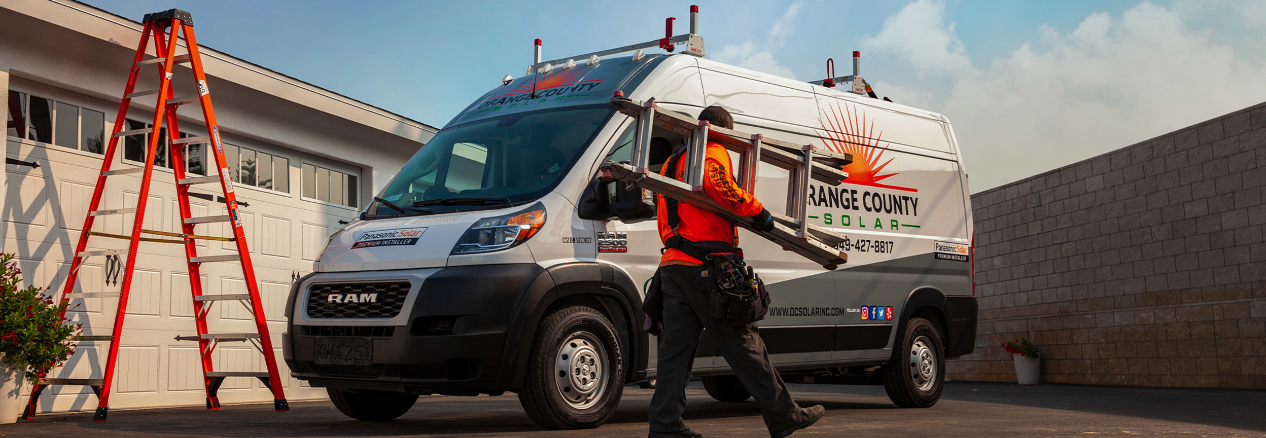 Personne tenant une échelle et marchant à côté d’un Ram ProMaster 2022, illustré en blanc, stationné devant un édifice