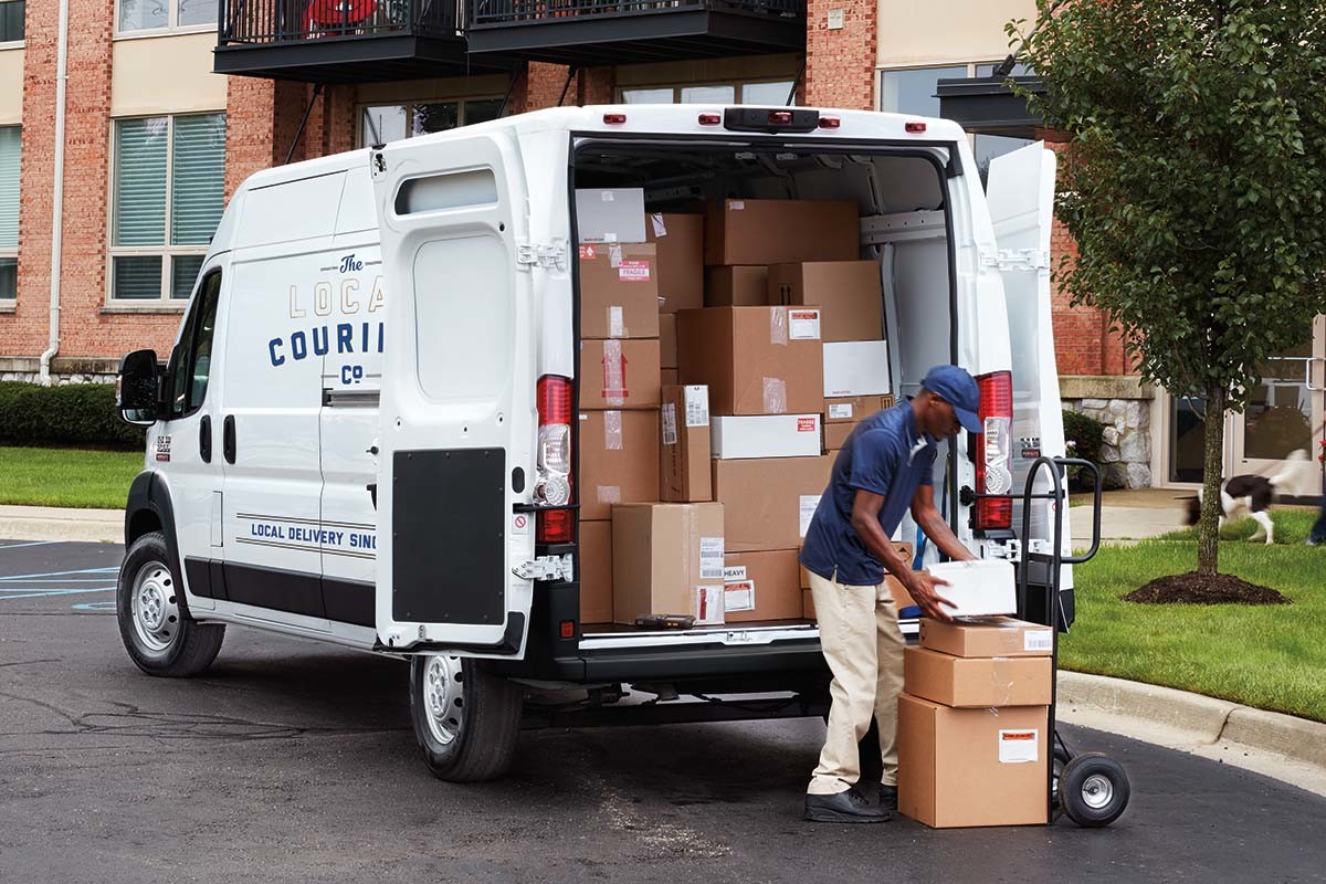 Un Ram ProMaster blanc 2023 rempli de boîtes en carton en cours de déchargement.