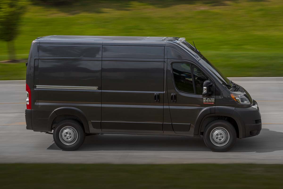 Vue latérale d'un Ram ProMaster gris 2023 roulant sur une route.