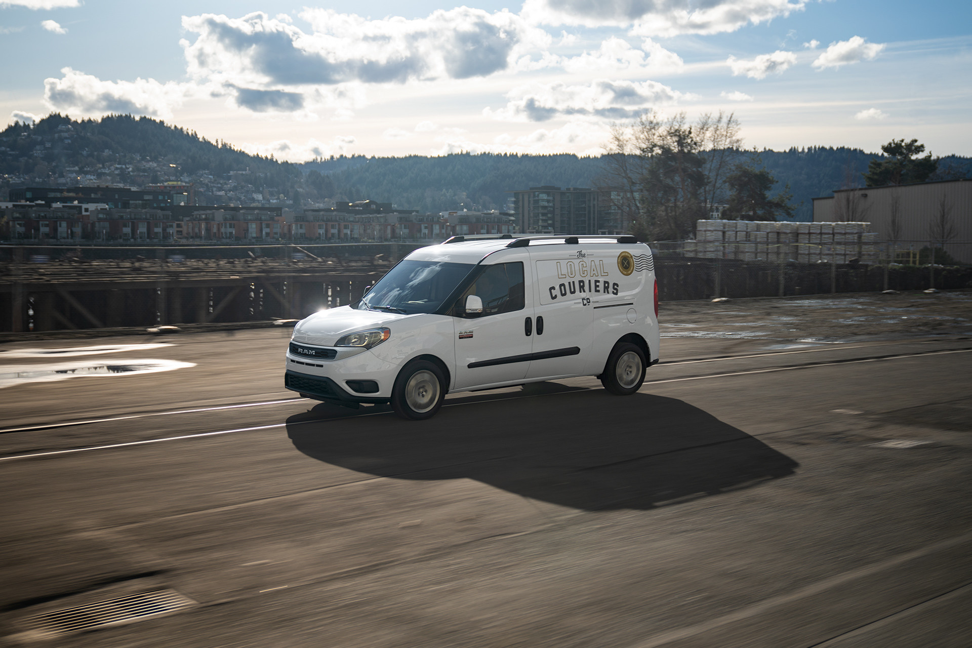 Side view of the white 2019 Ram ProMaster City driving on a country road
