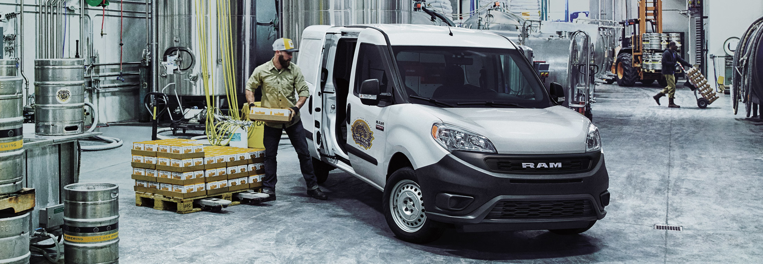 White 2021 Ram ProMaster City parked in a brewery. A worker is loading packages through the side door.