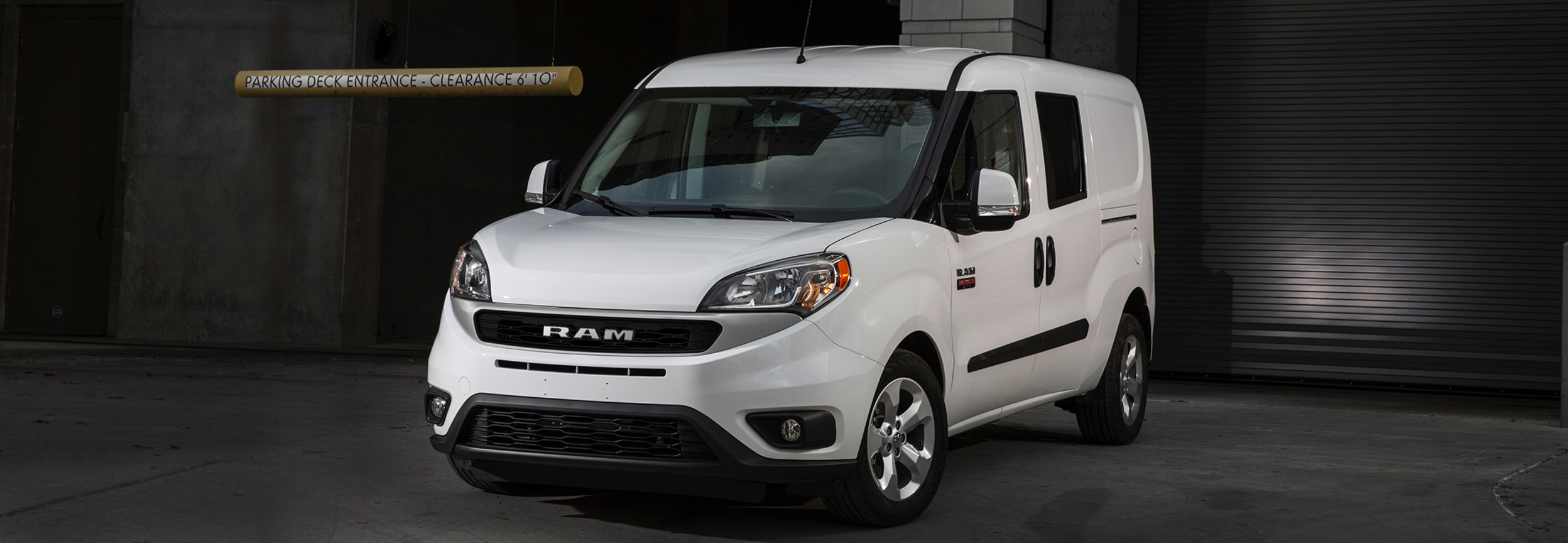 Un Ram ProMaster City 2021 blanc stationné devant les portes d’un quai de chargement.