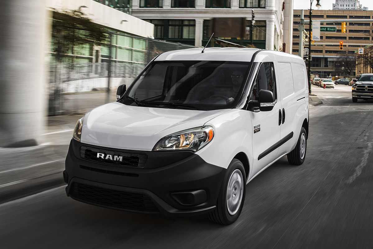 White 2021 Ram ProMaster City driving on city street.