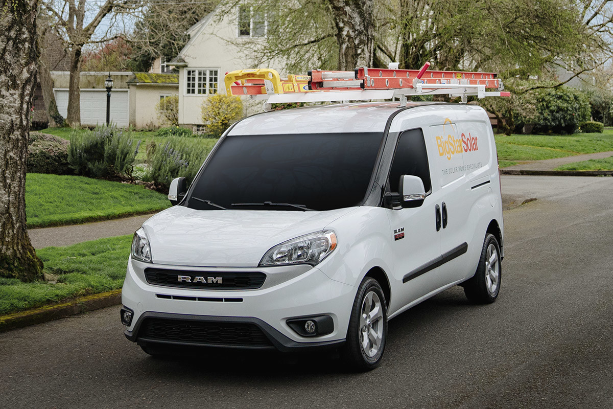 Ram ProMaster City 2021 blanc garé dans une rue résidentielle. Il est personnalisé par un porte-échelle de toit et un logo d’entreprise.