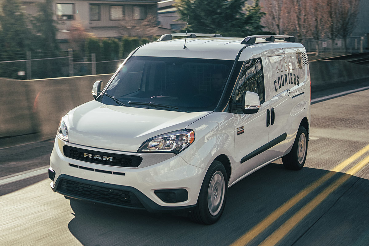 White 2021 Ram ProMaster City driving on a residential street.