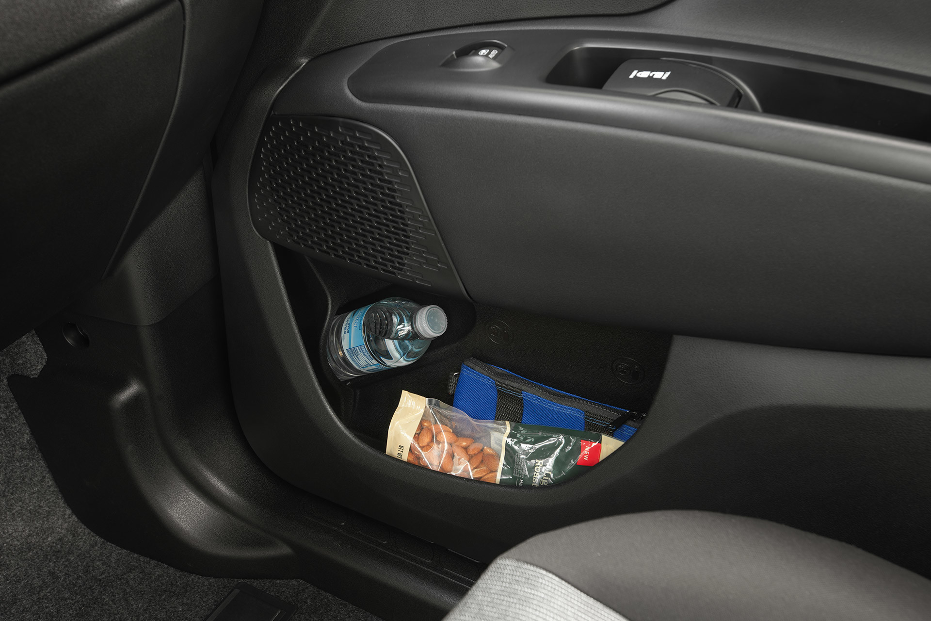 Close up of the passenger door storage compartment holding a water bottle, snack and pencil case.