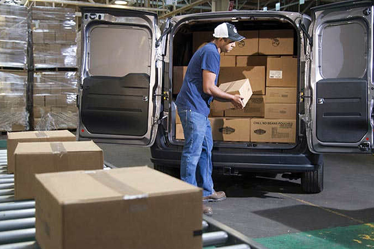 A person loading boxes onto a 2022 Ram ProMaster City.