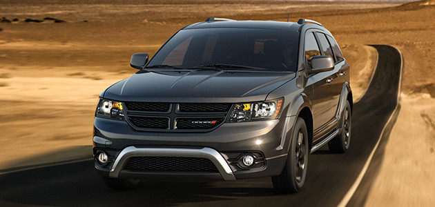 Un Dodge Journey 2019 gris roulant sur une autoroute à travers des plaines sablonneuses.