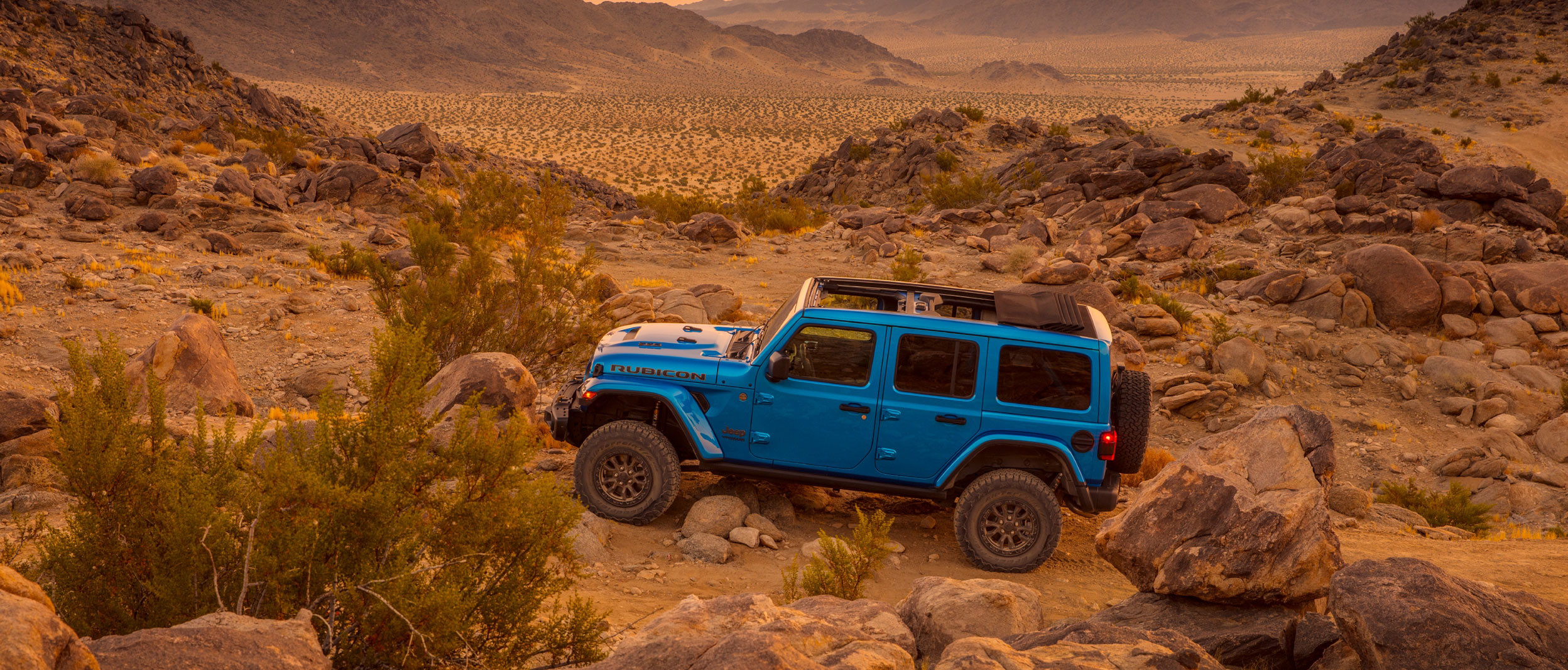Vue latérale d’un Jeep Wrangler Rubicon bleu stationné dans les bad-lands.