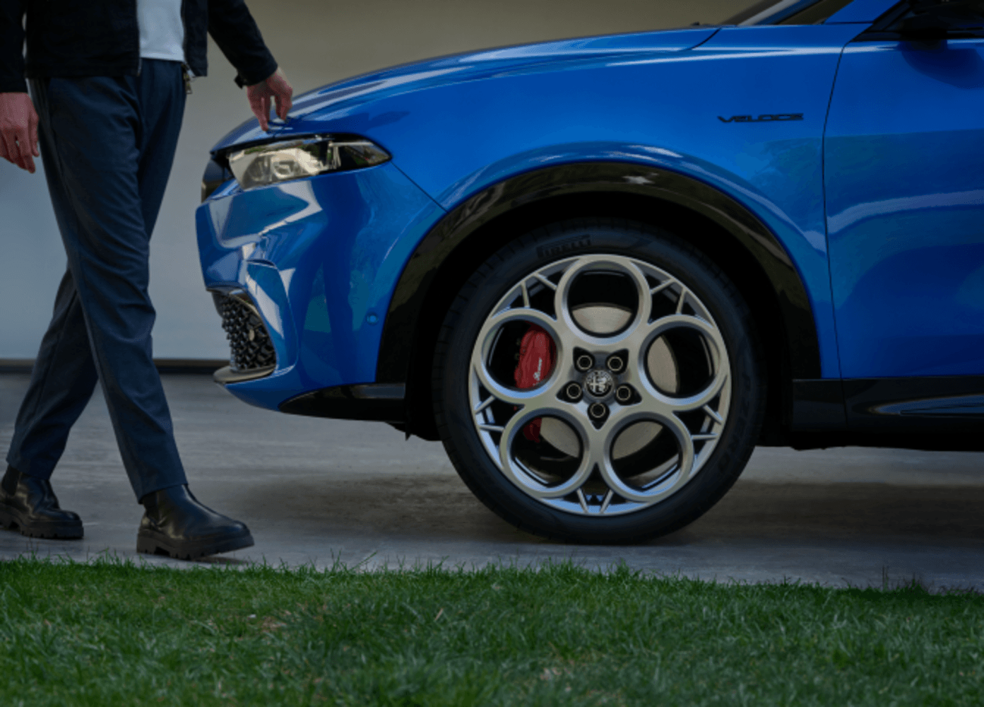 Vue de profil d’un Alfa Romeo VHR 2023 bleu garé à l’extérieur avec une personne qui marche devant le véhicule.