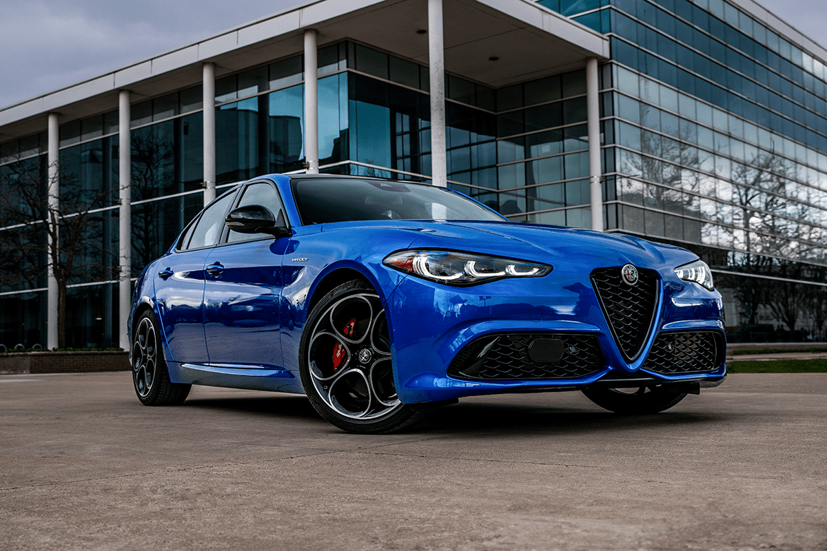 Anodized Blue Metallic 2025 Alfa Romeo Giulia parked in front of a modern glass building.
