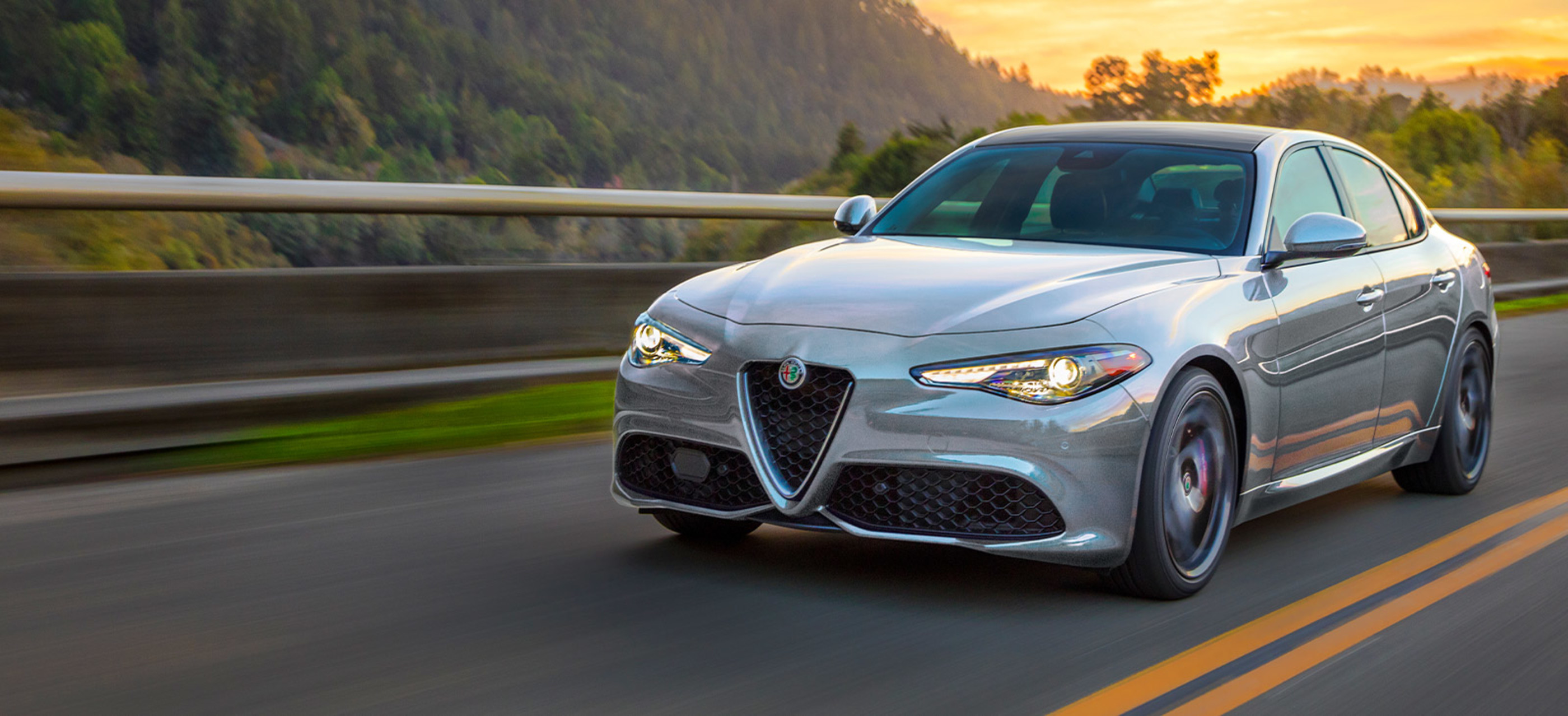 Front view of a silver Alfa Romeo Giulia, being driven on road in the mountains