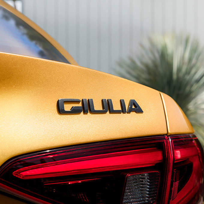 A close up view of the Giulia logo on the trunk of a yellow 2021 Alfa Romeo Giulia